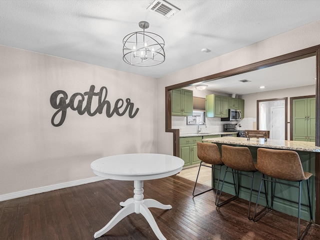 dining room featuring dark wood finished floors, visible vents, an inviting chandelier, a textured ceiling, and baseboards