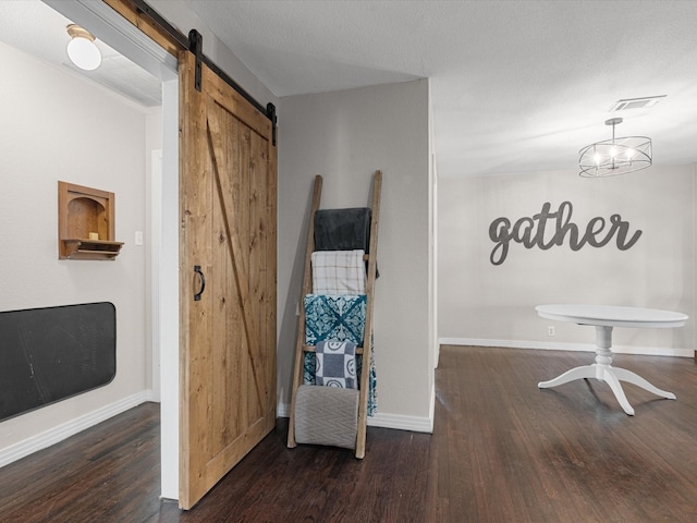 interior space with a barn door, visible vents, dark wood finished floors, and baseboards