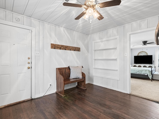 sitting room with dark wood-style floors, built in features, and a ceiling fan