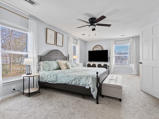 bedroom with light colored carpet, ceiling fan, visible vents, and baseboards