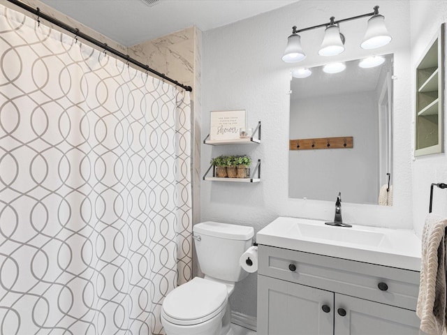 bathroom with a textured wall, vanity, and toilet