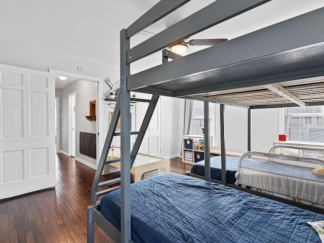 bedroom with dark wood-style floors, a textured ceiling, and baseboards