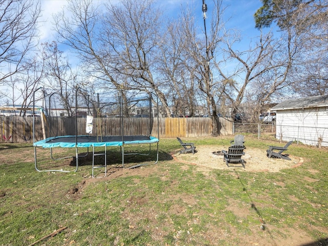 view of yard with a trampoline, an outdoor fire pit, and a fenced backyard