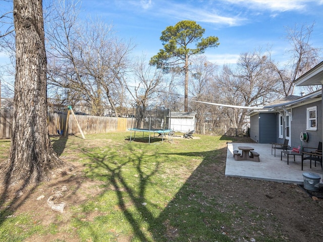 view of yard with a trampoline, a patio, a storage unit, a fenced backyard, and an outdoor structure