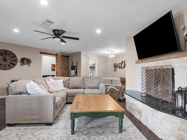 living room featuring a barn door, visible vents, light wood-style flooring, and recessed lighting