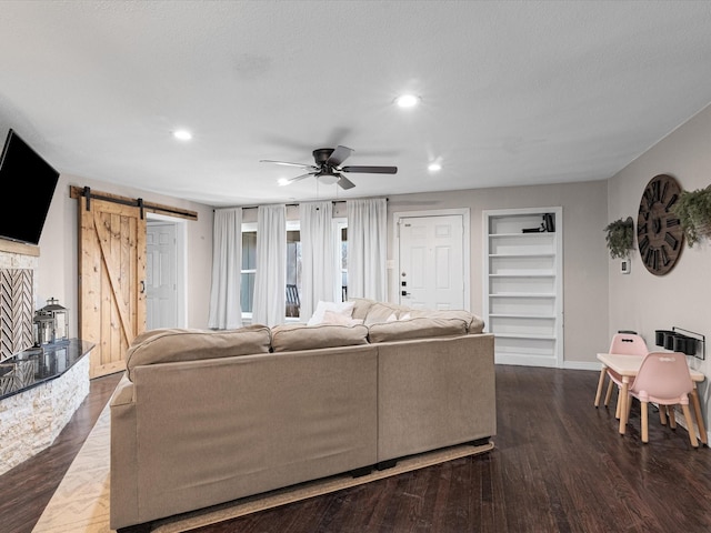 living area featuring dark wood-type flooring, a barn door, recessed lighting, and built in features