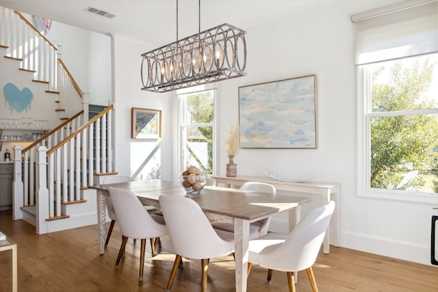 dining room featuring light wood finished floors, plenty of natural light, visible vents, and a chandelier