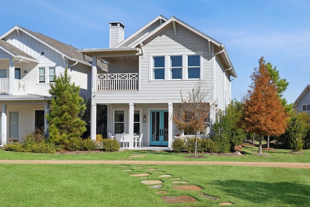 rear view of property featuring a balcony, a chimney, and a lawn