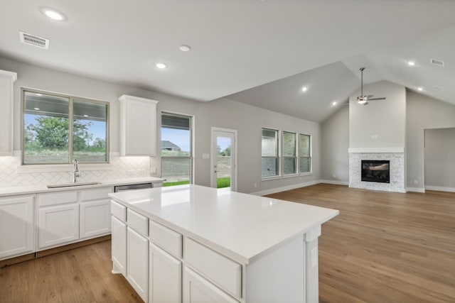 kitchen featuring a sink, white cabinetry, open floor plan, light countertops, and a center island