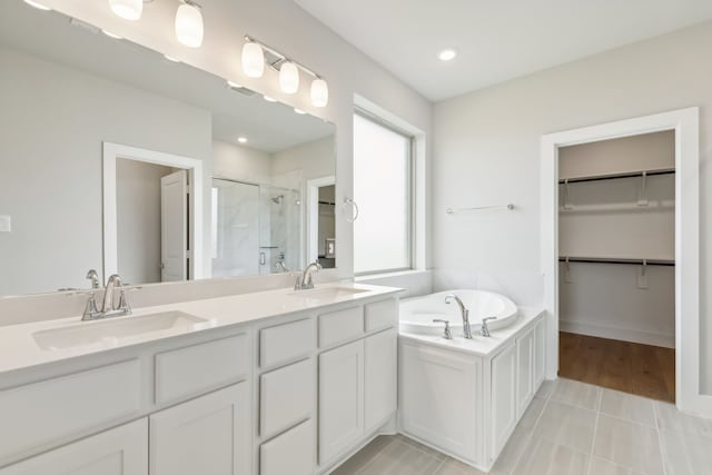 bathroom with double vanity, a sink, a shower stall, and a bath