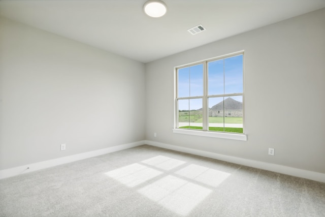 spare room featuring baseboards, visible vents, and light colored carpet