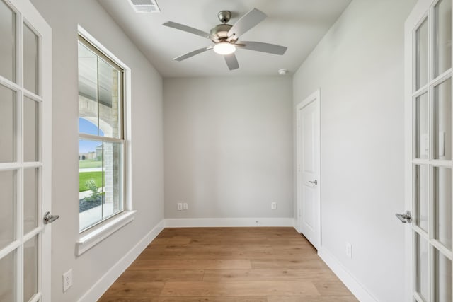 unfurnished room featuring light wood-style floors, baseboards, a wealth of natural light, and french doors