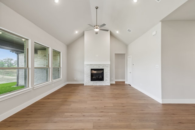 unfurnished living room with light wood finished floors, baseboards, a glass covered fireplace, high vaulted ceiling, and recessed lighting