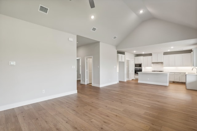 unfurnished living room with high vaulted ceiling, visible vents, ceiling fan, and light wood finished floors