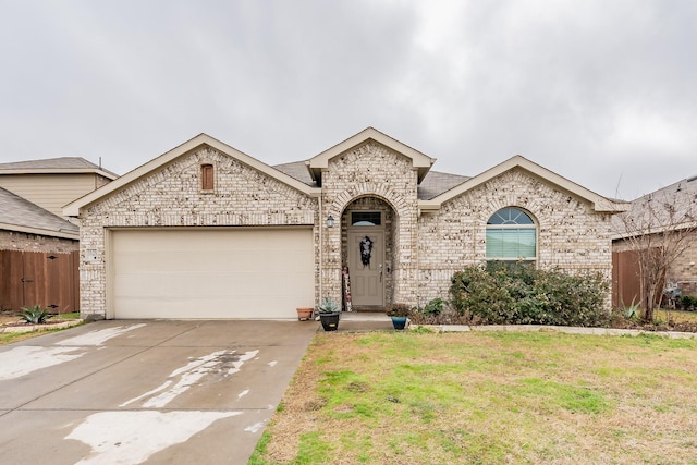 french country inspired facade featuring a garage, driveway, fence, a front lawn, and brick siding