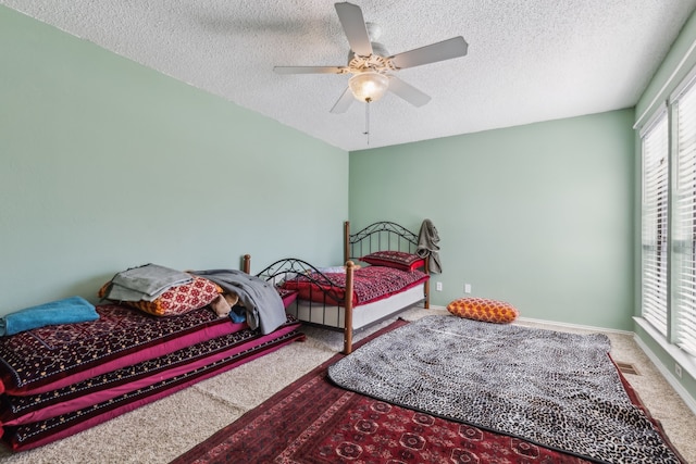 carpeted bedroom featuring a ceiling fan, visible vents, baseboards, and a textured ceiling