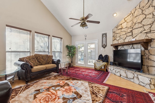 living room with a textured ceiling, high vaulted ceiling, wood finished floors, a ceiling fan, and french doors