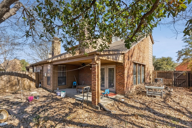 rear view of house featuring a patio area, a chimney, and a fenced backyard