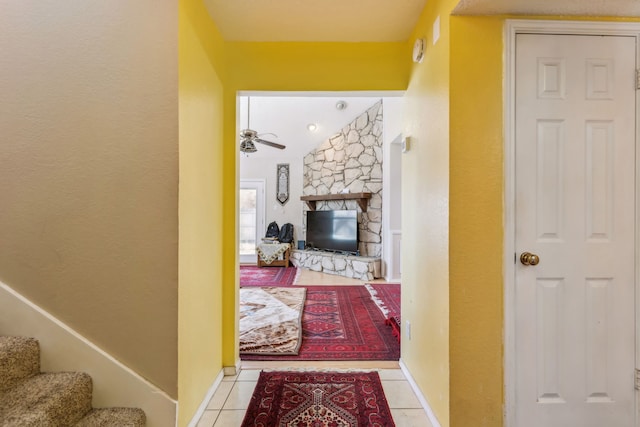 corridor with light tile patterned floors, stairway, and baseboards