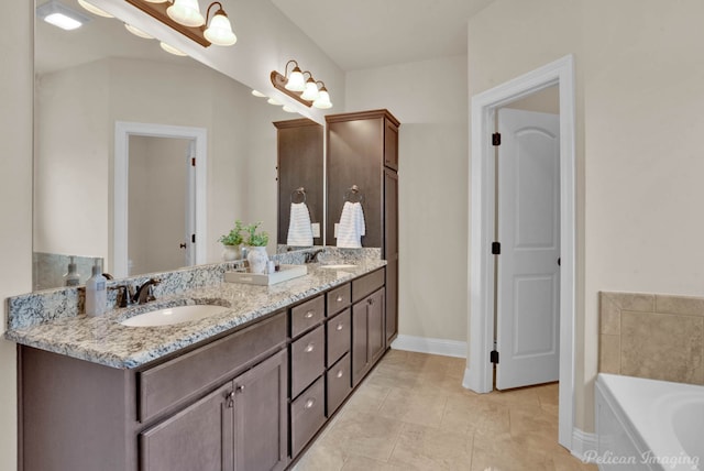 bathroom with a tub to relax in, a sink, baseboards, and double vanity