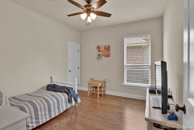 bedroom with light wood finished floors, ceiling fan, multiple windows, and baseboards