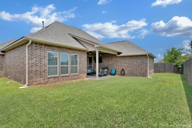 rear view of house featuring brick siding, a patio, a fenced backyard, and roof with shingles