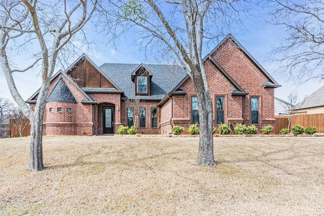 view of front of house featuring a shingled roof, a front yard, fence, and brick siding