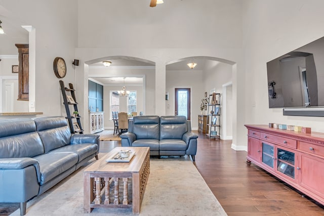 living room featuring arched walkways, ornamental molding, wood finished floors, and a high ceiling