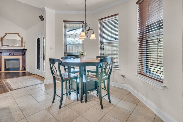 dining room featuring a tile fireplace, crown molding, baseboards, and light tile patterned floors