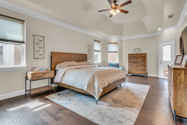 bedroom with a tray ceiling, dark wood finished floors, visible vents, ornamental molding, and baseboards