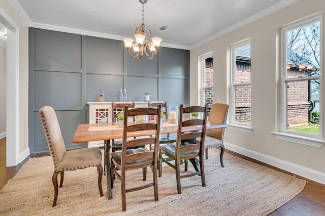 dining space featuring a notable chandelier, ornamental molding, plenty of natural light, and a decorative wall