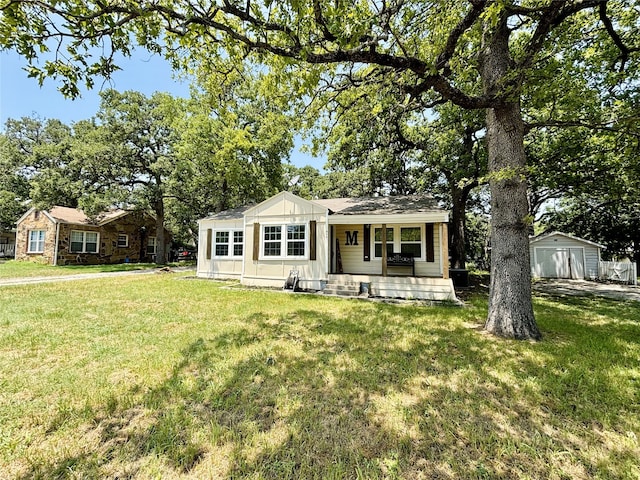 view of front of house with a front yard, covered porch, and an outdoor structure