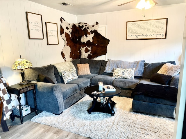 living area with ornamental molding, visible vents, ceiling fan, and wood finished floors