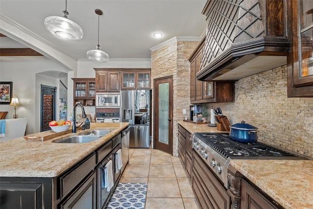 kitchen featuring stainless steel appliances, glass insert cabinets, a sink, an island with sink, and premium range hood