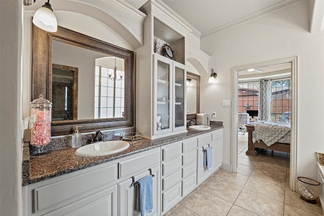 bathroom with ensuite bathroom, double vanity, ornamental molding, and a sink