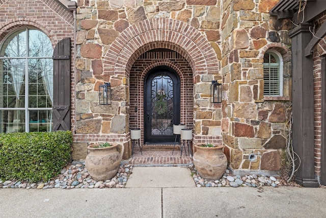 entrance to property featuring stone siding and brick siding