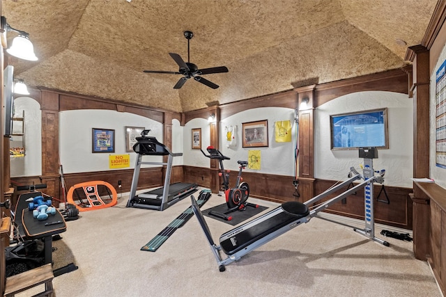 exercise area with ceiling fan, wood walls, vaulted ceiling, wainscoting, and carpet