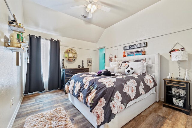 bedroom featuring lofted ceiling, visible vents, a ceiling fan, wood finished floors, and baseboards