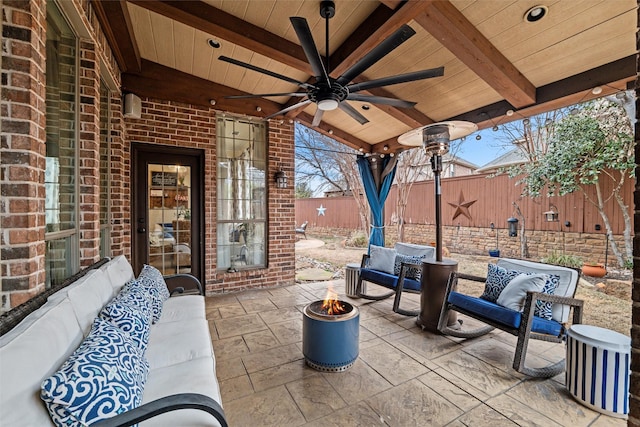 view of patio / terrace with a fenced backyard, a ceiling fan, and an outdoor living space with a fire pit