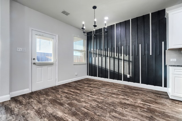 interior space featuring dark wood-type flooring, visible vents, baseboards, and an inviting chandelier