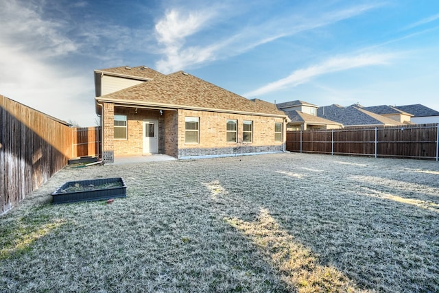 back of property featuring brick siding, roof with shingles, and a fenced backyard