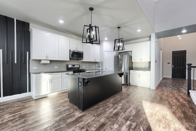 kitchen featuring stainless steel appliances, white cabinets, and an island with sink