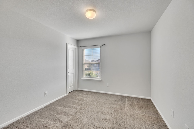 unfurnished room with a textured ceiling, carpet, and baseboards