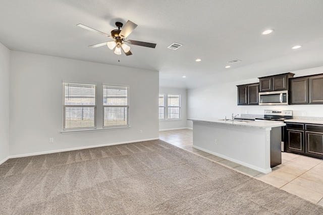 kitchen with light tile patterned floors, visible vents, a center island with sink, and appliances with stainless steel finishes