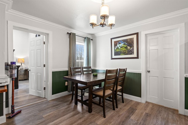 dining space with a chandelier, a wainscoted wall, ornamental molding, and wood finished floors