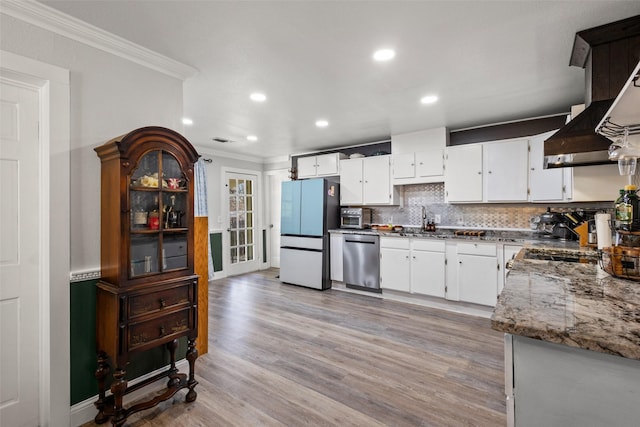 kitchen featuring light wood-style flooring, ornamental molding, stainless steel dishwasher, freestanding refrigerator, and tasteful backsplash