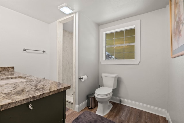 full bath with toilet, wood finished floors, vanity, baseboards, and a stall shower