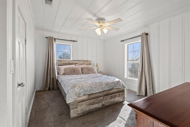 carpeted bedroom featuring a ceiling fan, multiple windows, and visible vents