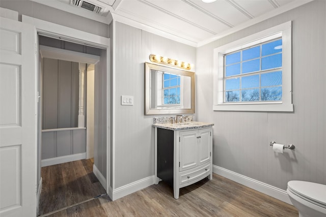 bathroom featuring baseboards, visible vents, toilet, wood finished floors, and vanity