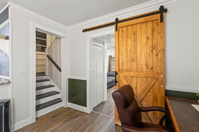 office space featuring a barn door, ornamental molding, and wood finished floors